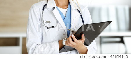 Unknown woman-doctor controls medication history record and medical exam results, close-up. Medicine concept Unknown woman-doctor controls medication history record and medical exam results, close-up. Medicine concept 69654143