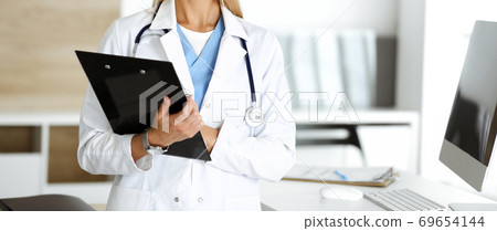Unknown woman-doctor controls medication history record and medical exam results, close-up. Medicine concept Unknown woman-doctor controls medication history record and medical exam results, close-up. Medicine concept 69654144