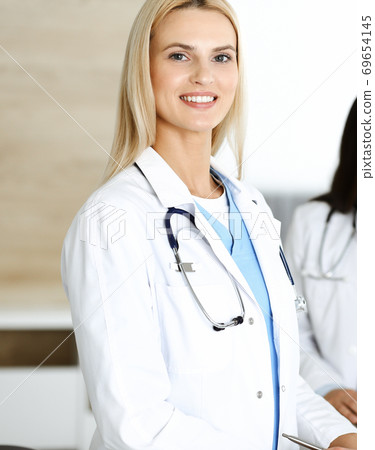 Doctor woman controls medication history records and exam results while using clipboard. Medicine and healthcare concept Doctor woman controls medication history records and exam results while using clipboard. Medicine and healthcare concept 69654145