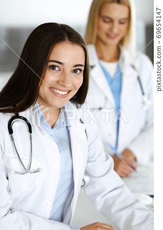 Doctor woman controls medication history records and exam results while using clipboard. Medicine and healthcare concept Doctor woman controls medication history records and exam results while using clipboard. Medicine and healthcare concept 69654147