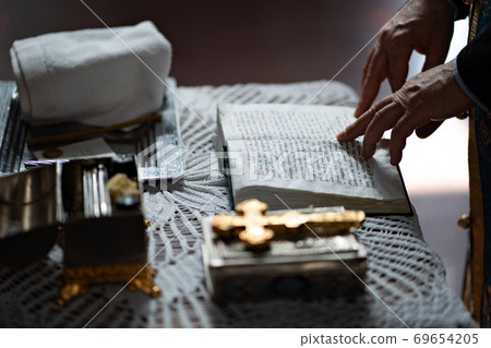 Orthodox priest reads prayer book at baptism Orthodox priest reads prayer book at baptism 69654205