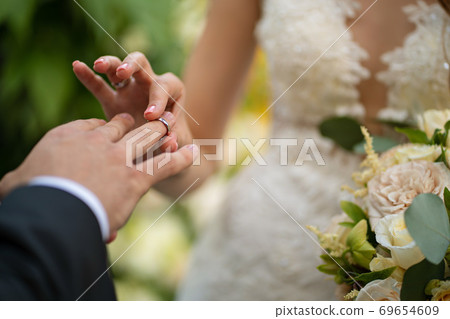 the bride and groom put on each other rings. the bride and groom put on each other rings. 69654609