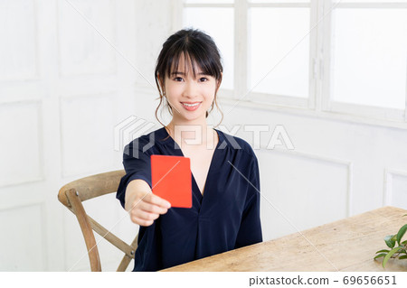 Young woman holding a red card in her hand 69656651