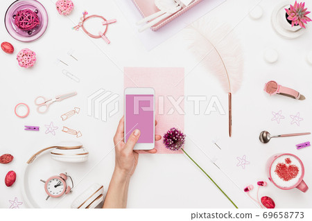 Smartphone in woman hand above artist workplace Smartphone in woman hand above artist workplace 69658773