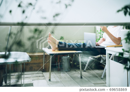 A man who works remotely on his balcony (no face) 69658869