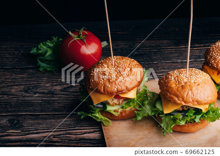 two delicious homemade hamburgers with meat, cheese, lettuce, tomato on a Board 69662125