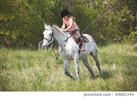 Little girl rides a white horse Little girl rides a white horse 69662344