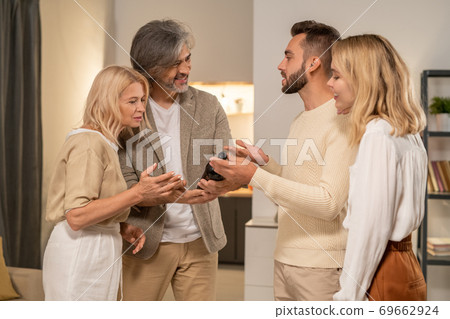 Mature female and her smiling husband looking at bottle of excellent red wine Mature female and her smiling husband looking at bottle of excellent red wine 69662924