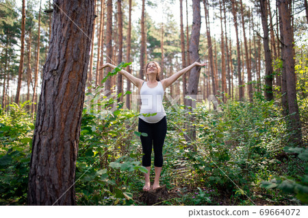 Portrait of happy barefoot pregnant woman outdoors in nature, doing exercise. 69664072