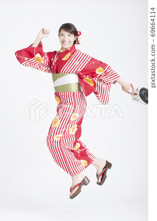 A woman in a yukata jumping 69664114