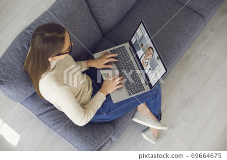 Family doctor online. Young girl at home on sofa with laptop makes video call to doctor. Top view. Family doctor online. Young girl at home on sofa with laptop makes video call to doctor. Top view. 69664675