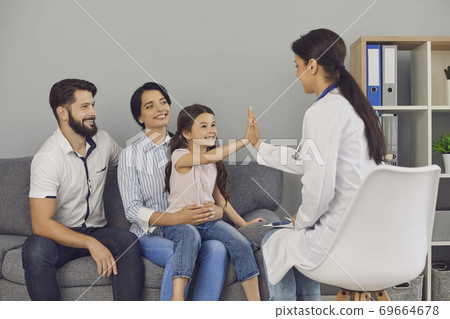 Smiling girl giving high five to woman doctor during successful consultation in clinic Smiling girl giving high five to woman doctor during successful consultation in clinic 69664678