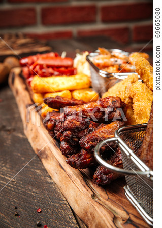 Fried beer snacks on the wooden board with sauces 69665080
