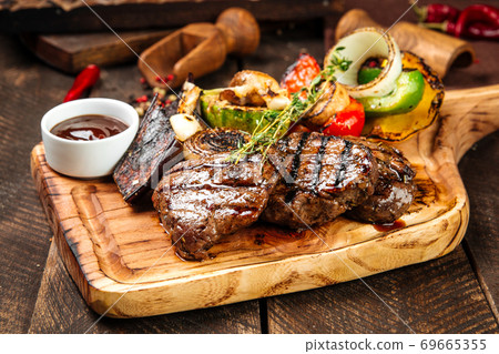 Grilled beef steaks with vegetables and sauce Grilled beef steaks with vegetables and sauce 69665355