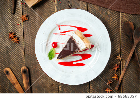 Tiramisu cake with berry sauce on the wooden table 69665357