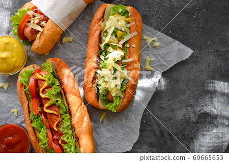 Hot dogs with various fillings. Dark background. food background with copy space. Top view. Hot dogs with mustard and ketchup, lettuce, cheese and tomatoes. Closeup 69665653