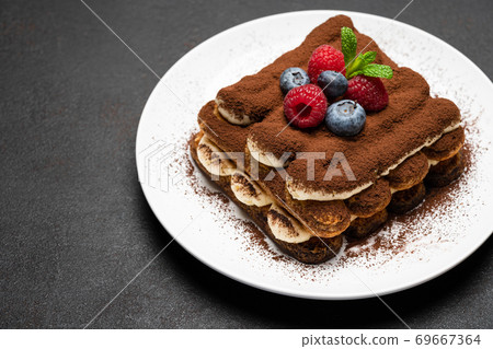 portion of Classic tiramisu dessert with raspberries and blueberries on dark concrete background portion of Classic tiramisu dessert with raspberries and blueberries on dark concrete background 69667364
