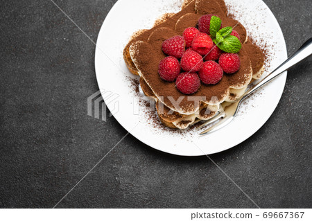 portion of Classic tiramisu dessert with raspberries on dark concrete background portion of Classic tiramisu dessert with raspberries on dark concrete background 69667367