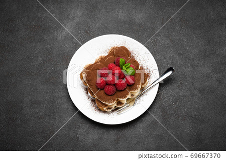 portion of Classic tiramisu dessert with raspberries on dark concrete background portion of Classic tiramisu dessert with raspberries on dark concrete background 69667370