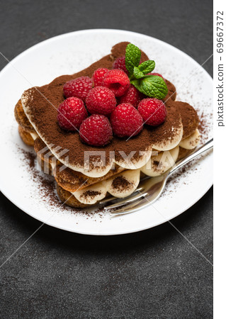 portion of Classic tiramisu dessert with raspberries on dark concrete background portion of Classic tiramisu dessert with raspberries on dark concrete background 69667372