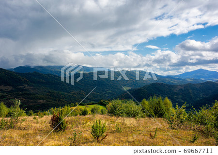 mountainous countryside in autumn. beautiful nature on a sunny day. dry grass on the meadow. ridge in the distance. clouds on the sky mountainous countryside in autumn. beautiful nature on a sunny day. dry grass on the meadow. ridge in the distance. clouds on the sky 69667711