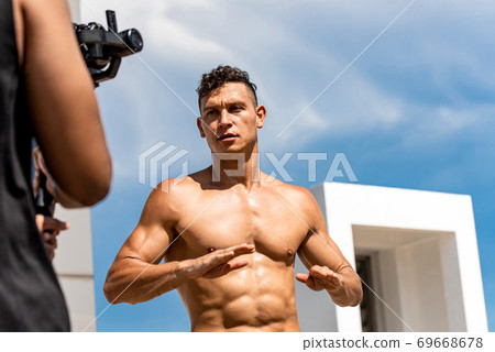 Muscular man fitness influencer recording exercise video clip 69668678