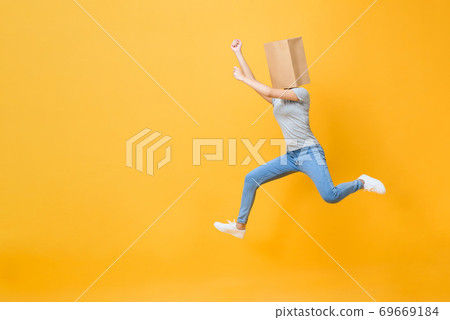 Anonymous woman with head covered with paper bag jumping Anonymous woman with head covered with paper bag jumping 69669184