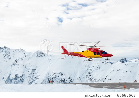 Mountain ski life rescue medic helicopter taking-off from station helipad to search injured skiers and help at accident. Emergency chopper at austrian alpine skiing resort. Alps landsape 69669665
