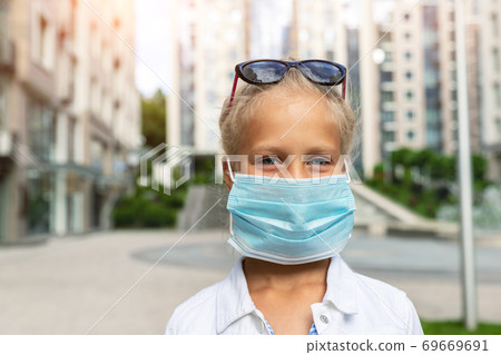 Cute adorable little caucasian happy blond girl in sunglasses wearing protective face mask due quarantine and covid-19 pandemic walking at city street . Smiling child walk at public place outdoor Cute adorable little caucasian happy blond girl in sunglasses wearing protective face mask due quarantine and covid-19 pandemic walking at city street . Smiling child walk at public place outdoor 69669691