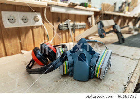 PPE respirator face half mask and ear protection equipment on wooden workbench of carpentry professional woodwork workshop. Worker safety and health protection tools concept 69669753