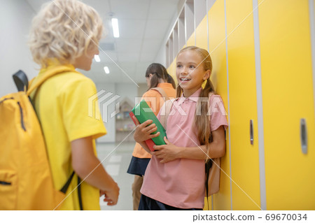 Boy and girl talking in the corridor standing near the lockers Boy and girl talking in the corridor standing near the lockers 69670034