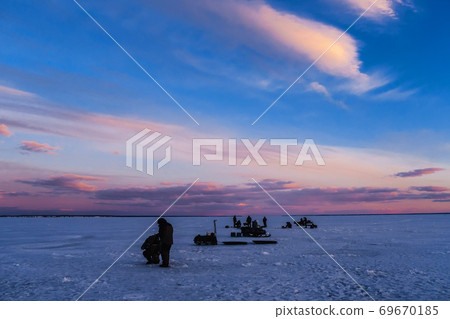 silhouettes of men fishermen and snowmobiles on winter fishing 69670185
