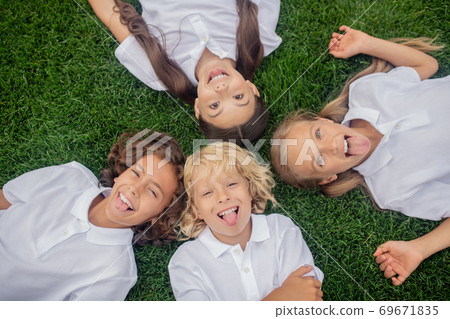 Children in white lying on the grass and smiling Children in white lying on the grass and smiling 69671835