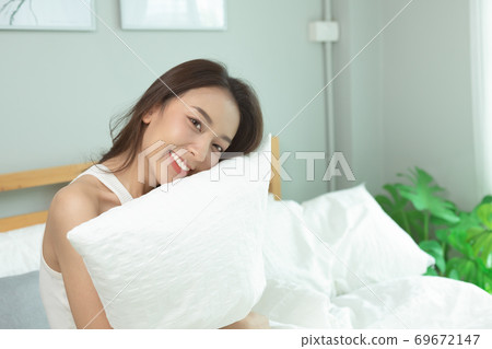 Asian women wake up happy and smile on white bed in bedroom. Asian women wake up happy and smile on white bed in bedroom. 69672147