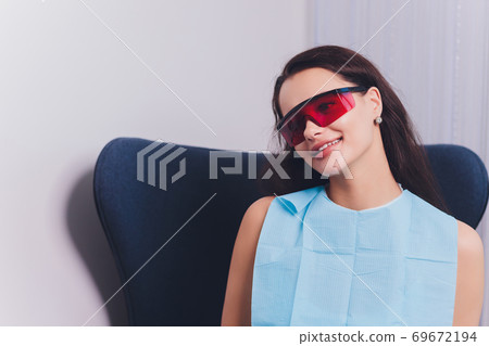 Close-up portrait of a female patient visiting dentist for teeth whitening in clinic,Teeth whitening procedure. 69672194