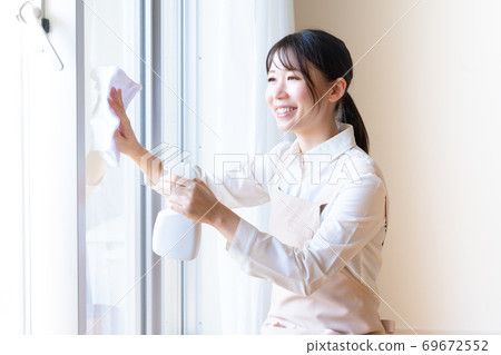 Young female staff on behalf of housework cleaning windows Young female staff on behalf of housework cleaning windows 69672552