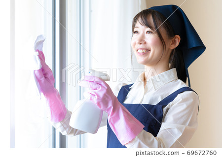 Young female staff on behalf of housework cleaning windows 69672760