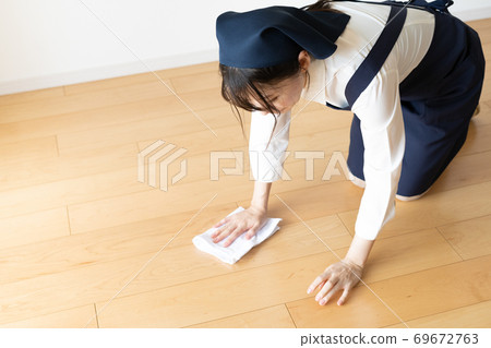 Young female staff on behalf of housework wiping the floor 69672763