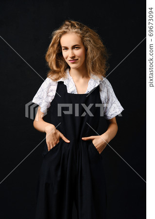 Satisfied young girl in pantsuit and shirt posing over black background Satisfied young girl in pantsuit and shirt posing over black background 69673094