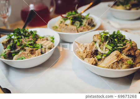pieces of fried meat with onions and barley on a white plate next to lettuce. 69673268