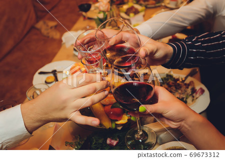 Close up shot of group of people clinking glasses with wine or champagne in front of bokeh background. older people hands. Close up shot of group of people clinking glasses with wine or champagne in front of bokeh background. older people hands. 69673312