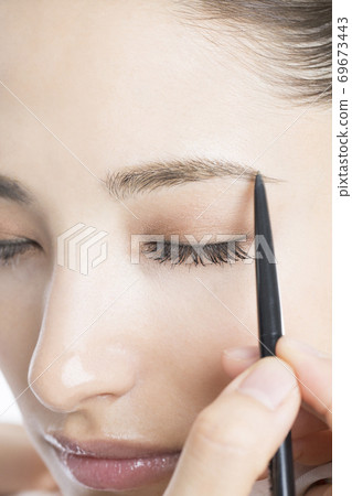 A woman drawing an eyebrow 69673443