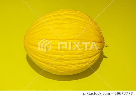 Yellow melon on bright yellow background. Food concept. Flat lay with shadow Yellow melon on bright yellow background. Food concept. Flat lay with shadow 69673777