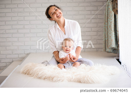 Mom and baby boy in diaper playing in sunny bedroom. Family havi Mom and baby boy in diaper playing in sunny bedroom. Family havi 69674045