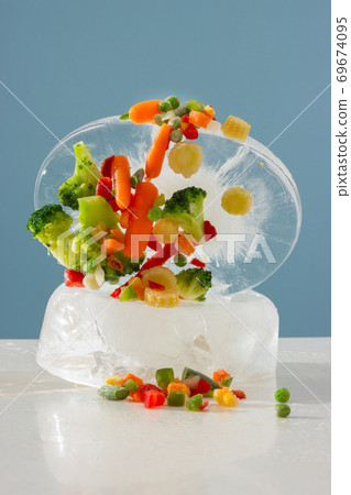 Frozen vegetables with a large piece of ice. Vertical orientation. Frozen vegetables with a large piece of ice. Vertical orientation. 69674095