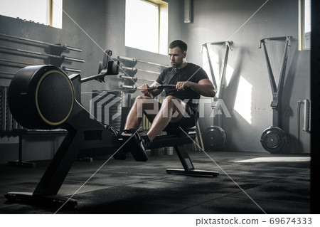 Athletic Male Do Hard Exercises With Rowing Machine . Athletic Male Do Hard Exercises With Rowing Machine . 69674333