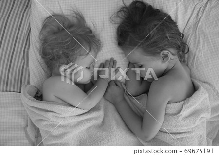 little sisters sleep together in bed at home. little sisters sleep together in bed at home. 69675191