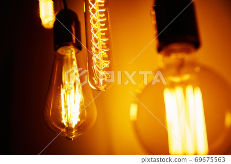 Set of a vintage light bulb on orange background, soft focus. Glowing edison bulb Set of a vintage light bulb on orange background, soft focus. Glowing edison bulb 69675563
