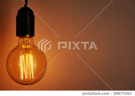 Vintage light bulb on orange background, copy space. Glowing edison bulb 69675565