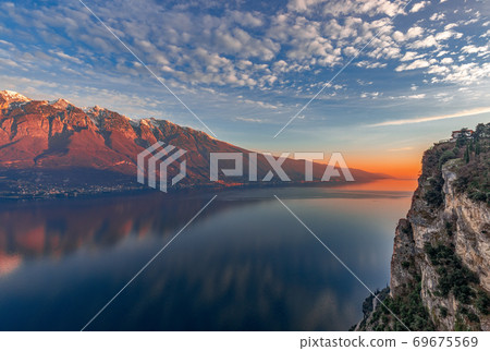 Stunning sunset on Lake Garda. View of the snowy Alps painted by the setting sun Stunning sunset on Lake Garda. View of the snowy Alps painted by the setting sun 69675569